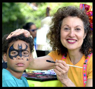 Boy gets his face painted aBoy face painted as batman superhero by facepainter Daisy Doodle at Brooklyn streetfair