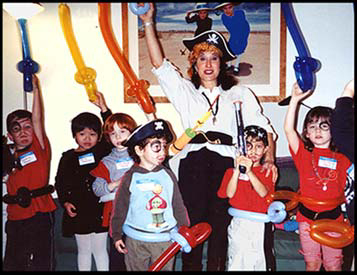 Children raise balloon swords with Captain Daisy Doodle at pirate birthday party in Connecticut