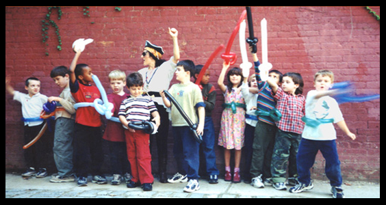 Children hold balloons swords up for photo at pirate birthday party outside in Manhattan NY