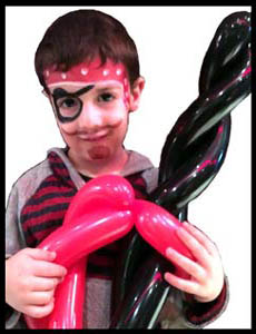 Child is facepainted as a pirate and holds his twisted birthday party balloon sword in Bronx NY